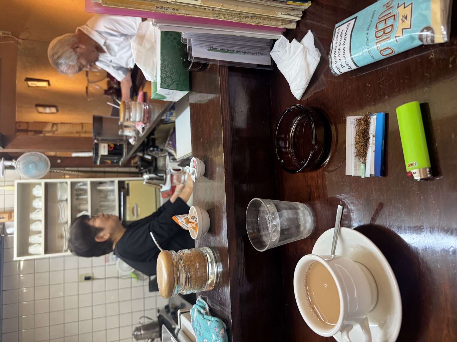 A traditional smoking-permitted coffee shop counter, ashtray and rolling tobacco included.
