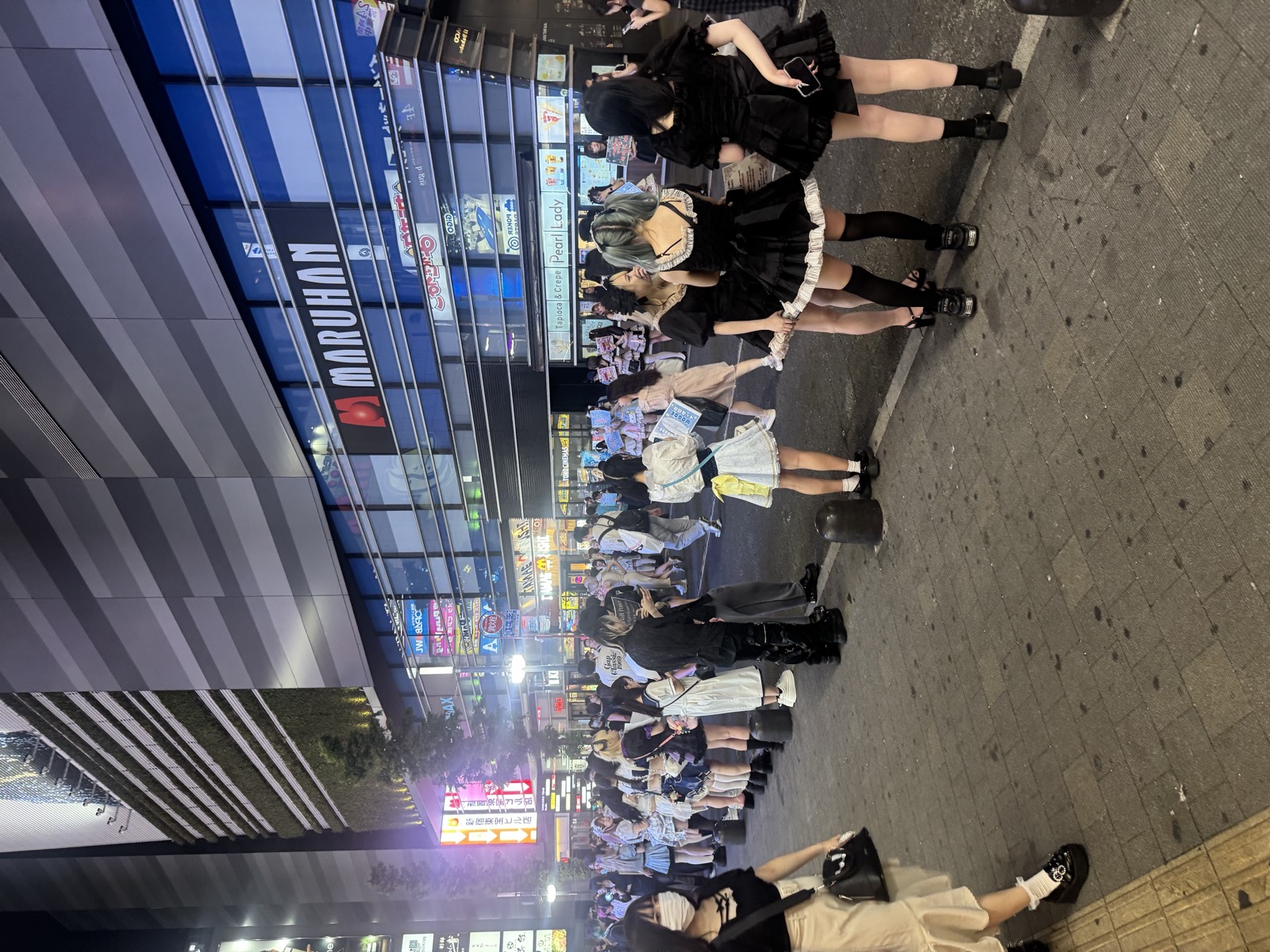 Maid cafe staff and crowds lining the street at night.