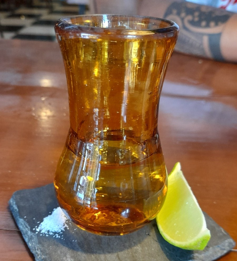 A shot of tequila with lime and salt at a Mexican bar.